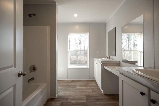 full bath featuring two vanities, shower / bath combination, wood finished floors, and a sink