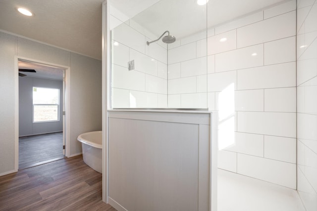 bathroom featuring baseboards, recessed lighting, wood finished floors, a walk in shower, and a soaking tub