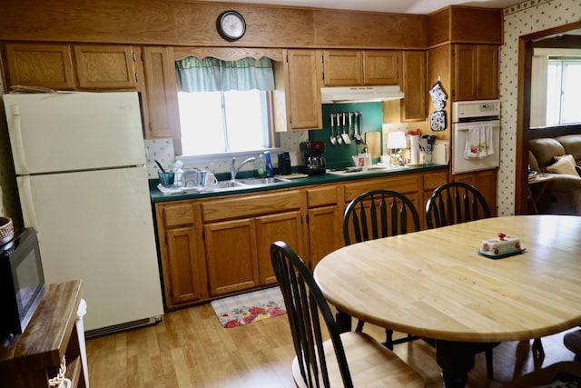 3421 Franklin Dr, Chattanooga, TN 37419 - kitchen with white appliances, under cabinet range hood, dark countertops, and light wood-style flooring