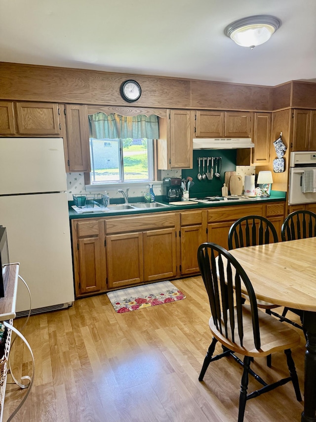 3421 Franklin Dr, Chattanooga, TN 37419 - kitchen featuring white appliances, light wood-type flooring, brown cabinets, under cabinet range hood, and a sink