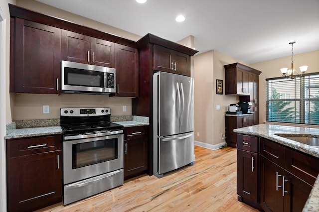 745 Soaring Eagle Cir, Hixson, TN 37343 - kitchen featuring pendant lighting, a chandelier, light stone counters, light wood-style flooring, and appliances with stainless steel finishes