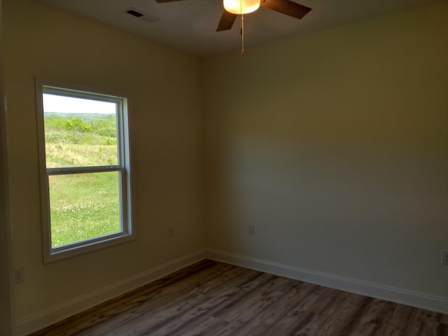 spare room with a ceiling fan, baseboards, a wealth of natural light, and wood finished floors