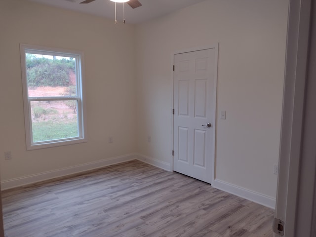 empty room with baseboards, ceiling fan, a wealth of natural light, and light wood-type flooring
