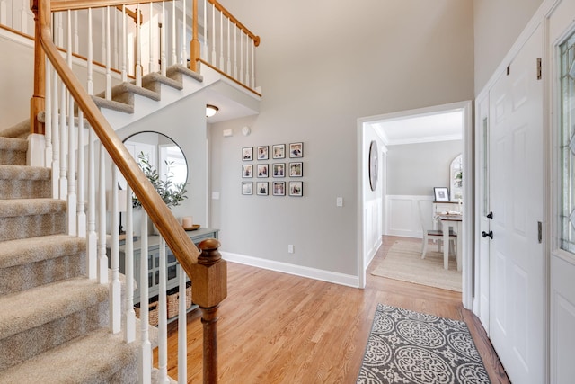 stairs featuring ornamental molding, a high ceiling, and wood finished floors