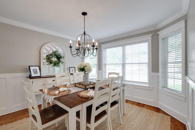 dining space featuring a wainscoted wall, light wood-style floors, a decorative wall, and an inviting chandelier
