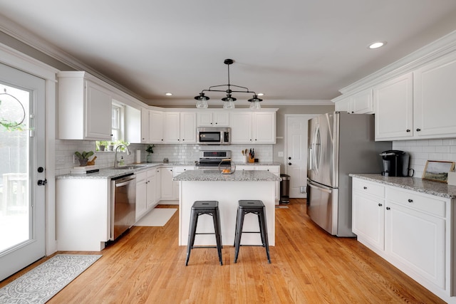 kitchen with a sink, stainless steel appliances, a kitchen island, and white cabinets
