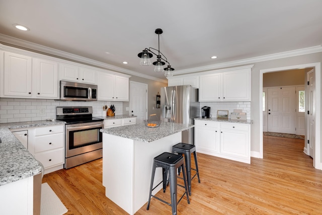 kitchen featuring a center island, stainless steel appliances, white cabinetry, backsplash, and ornamental molding