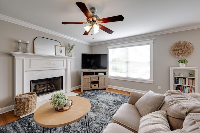 living area featuring baseboards, ceiling fan, a premium fireplace, and crown molding
