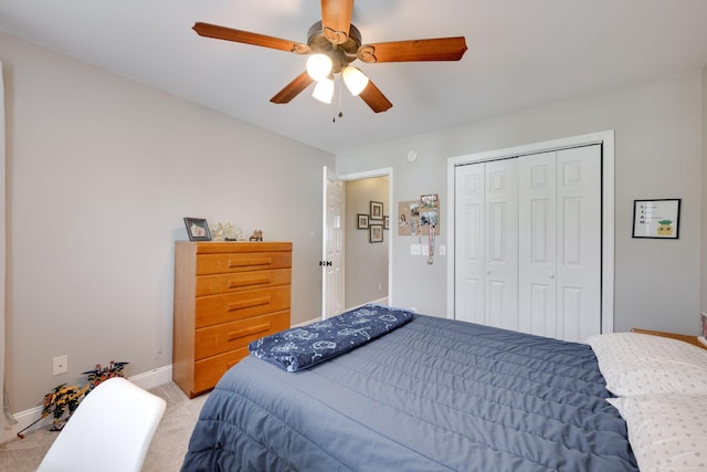 bedroom with a closet, light carpet, baseboards, and a ceiling fan