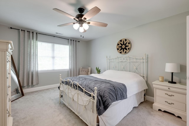 bedroom featuring light colored carpet, visible vents, baseboards, and ceiling fan