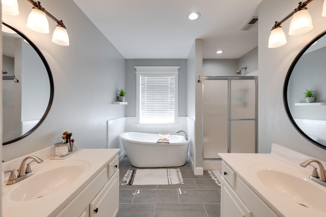 full bath featuring a shower stall, two vanities, and a sink