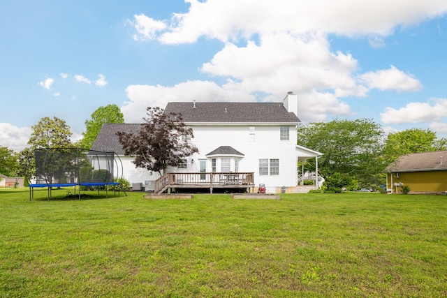 back of house with a lawn, a trampoline, a chimney, and a deck