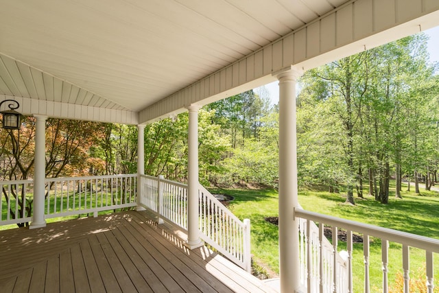 wooden terrace with a lawn and covered porch