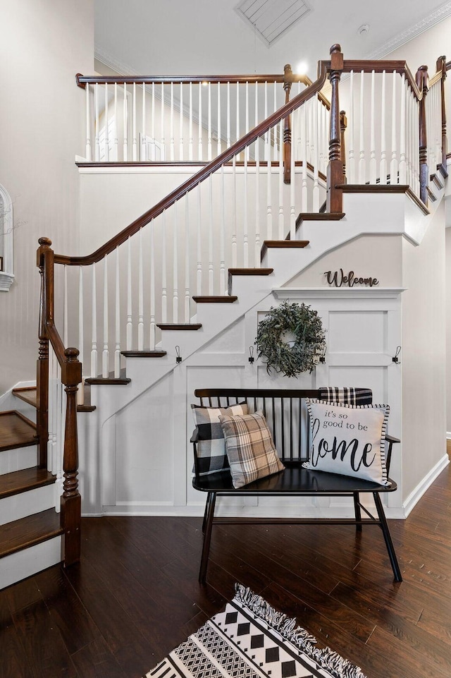 staircase with crown molding, wood-type flooring, and baseboards