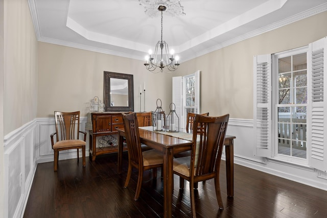 dining area featuring dark wood-type flooring, plenty of natural light, a chandelier, and a tray ceiling