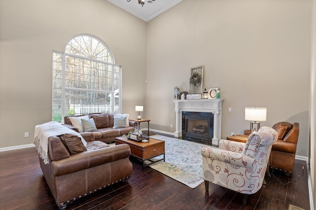 living room featuring a high ceiling, a fireplace with flush hearth, baseboards, ornamental molding, and hardwood / wood-style floors