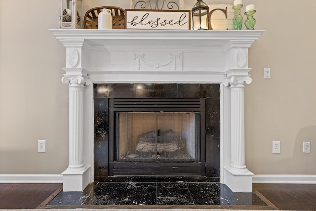 details featuring wood finished floors, a tiled fireplace, and baseboards