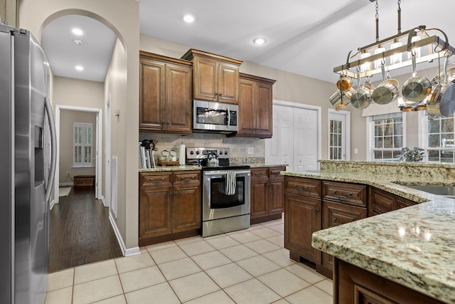 kitchen with recessed lighting, a sink, stainless steel appliances, decorative backsplash, and light stone counters