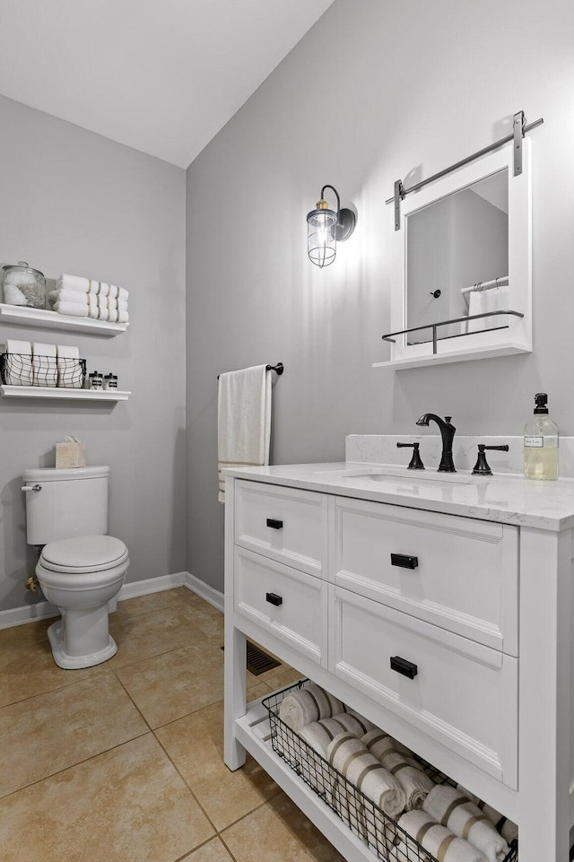 bathroom featuring toilet, tile patterned flooring, vanity, and baseboards