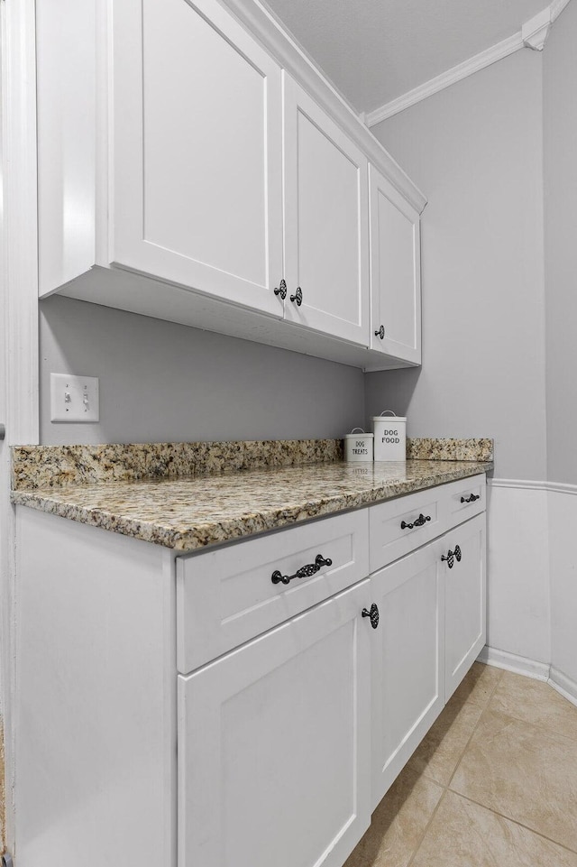 laundry area with ornamental molding, light tile patterned floors, and baseboards