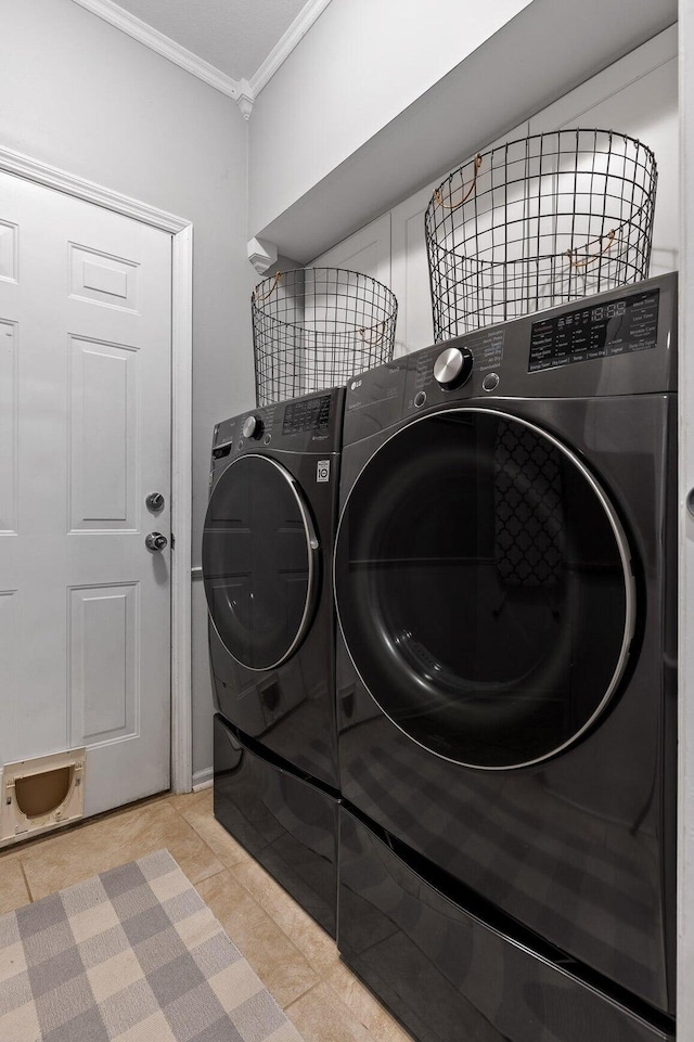 laundry area featuring ornamental molding, washing machine and dryer, light tile patterned floors, and laundry area