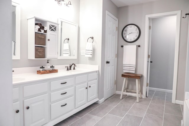 full bathroom with tile patterned flooring, a sink, double vanity, and baseboards