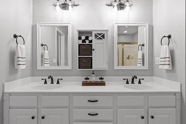 bathroom with double vanity, a shower with shower door, and a sink