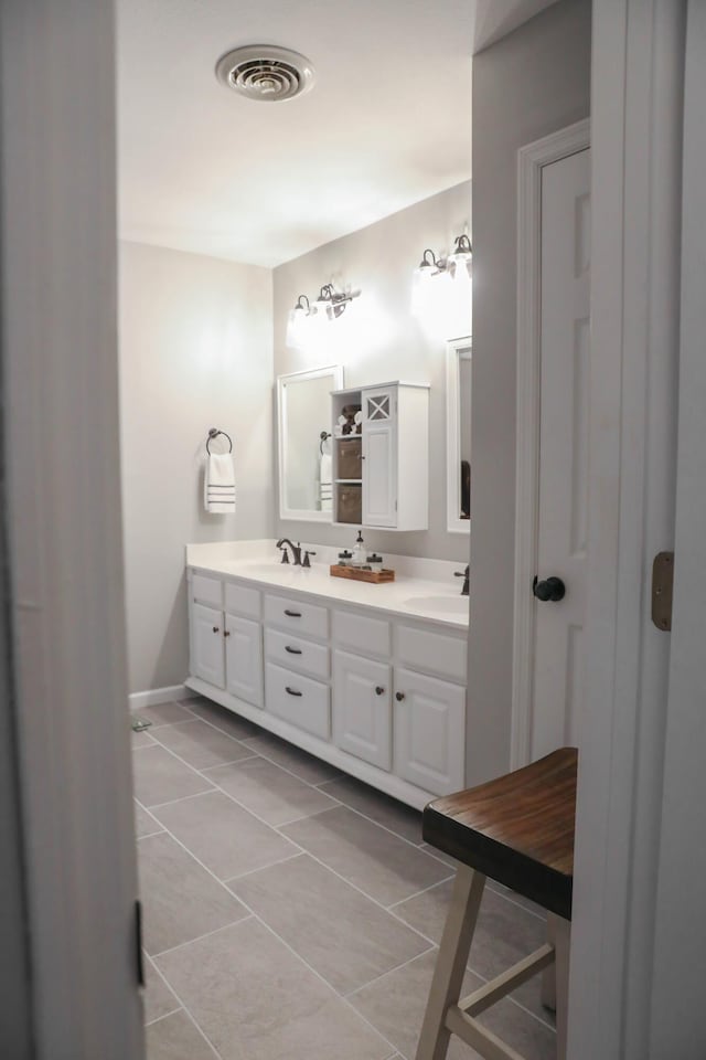 full bathroom featuring a sink, double vanity, visible vents, baseboards, and tile patterned floors