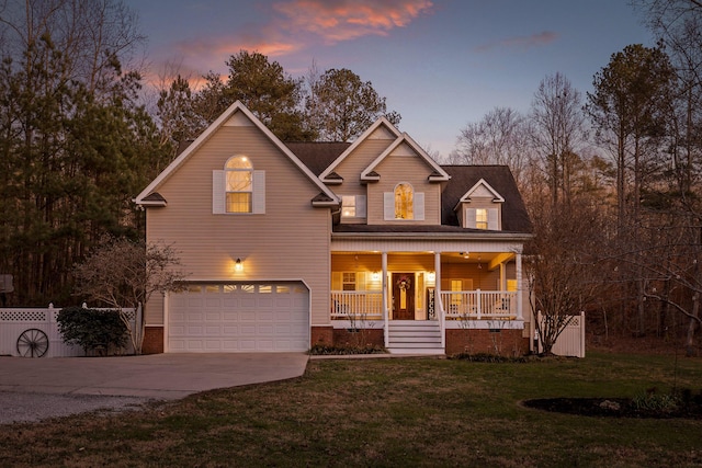 traditional-style house with covered porch, fence, a front yard, concrete driveway, and an attached garage