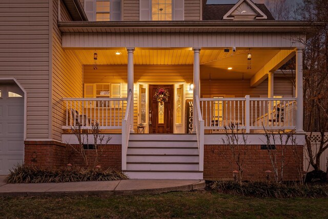 view of exterior entry featuring a garage and covered porch