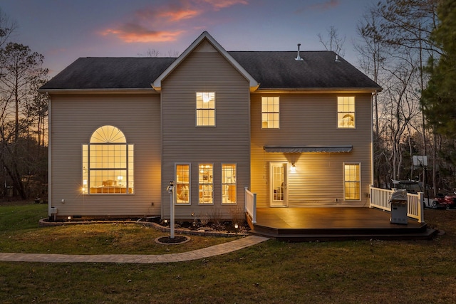 back of property at dusk with a yard and a wooden deck
