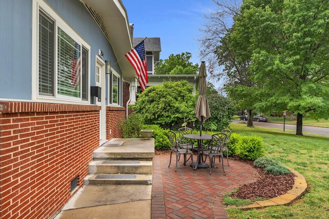 view of side of home with a lawn, a patio area, and brick siding
