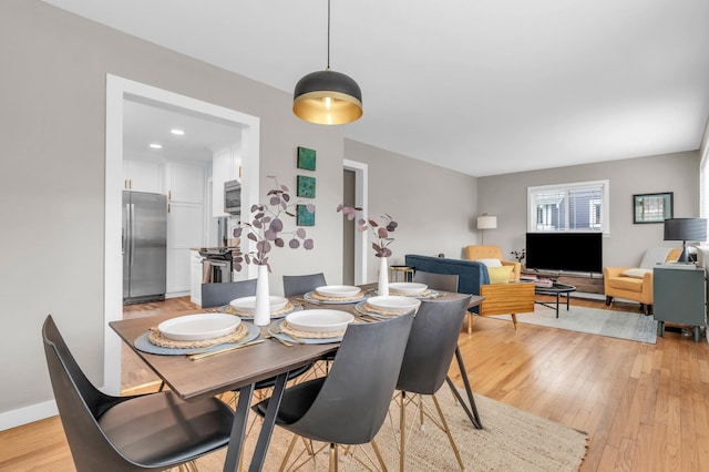 dining area with light wood-type flooring and baseboards