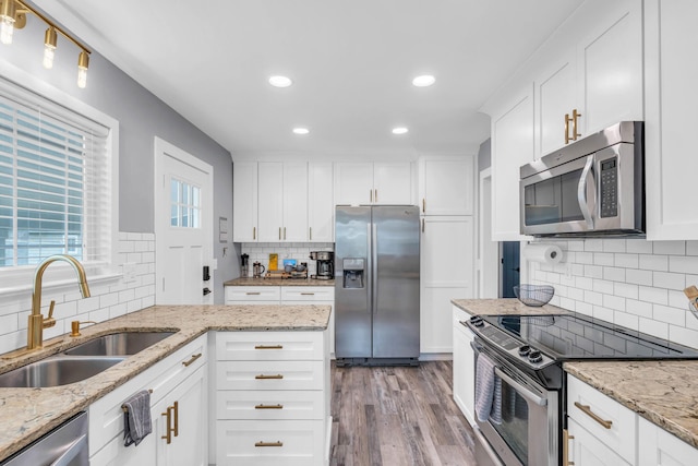 kitchen with tasteful backsplash, stainless steel appliances, white cabinets, and a sink