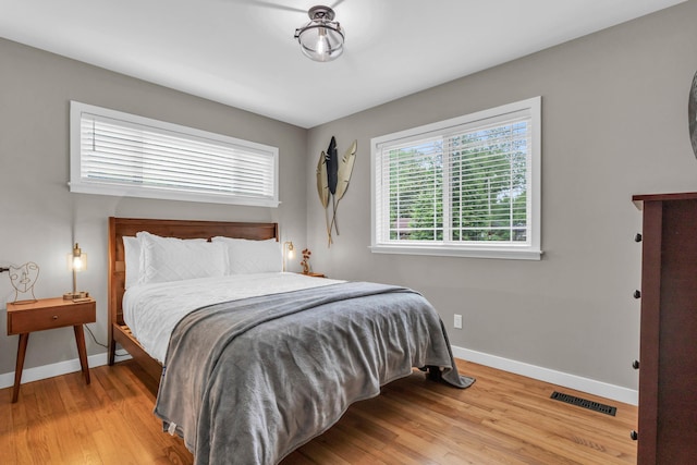 bedroom featuring visible vents, light wood-style flooring, and baseboards