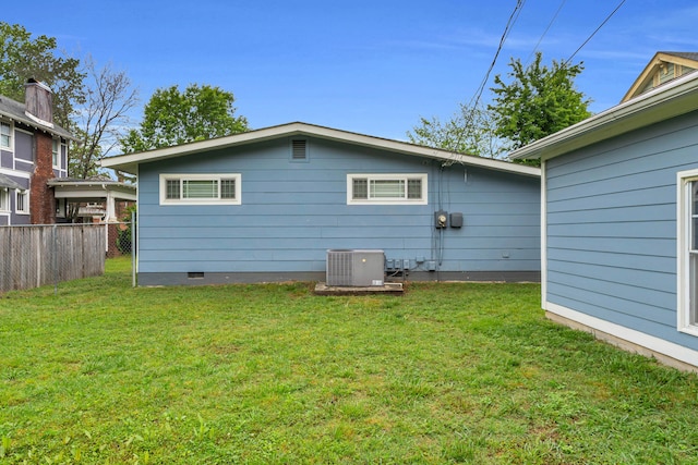 back of property with fence, cooling unit, a yard, and crawl space