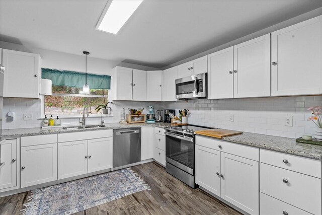 3818 Granada Dr, Chattanooga, TN 37411 - kitchen featuring appliances with stainless steel finishes, a sink, white cabinets, tasteful backsplash, and decorative light fixtures