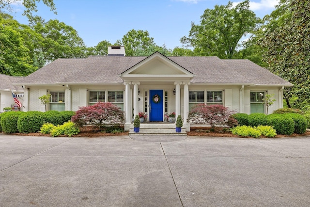 view of front of property featuring brick siding, a shingled roof, and a chimney