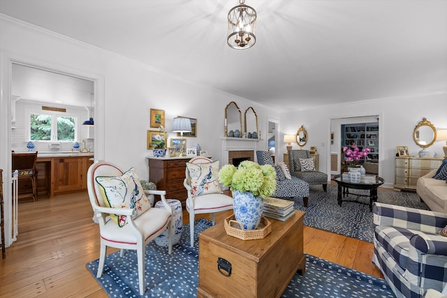 living area with crown molding, light wood finished floors, and a brick fireplace