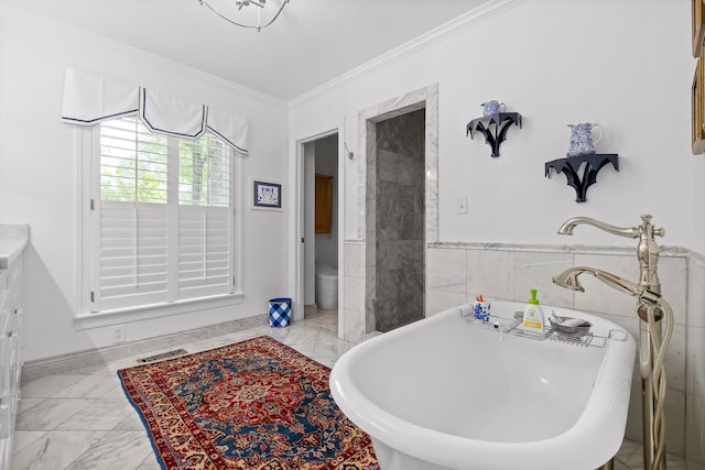 bathroom featuring visible vents, wainscoting, marble finish floor, ornamental molding, and a soaking tub