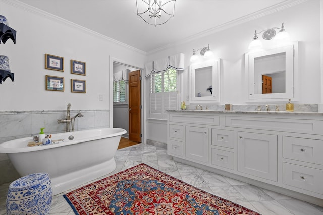 bathroom with double vanity, a freestanding bath, marble finish floor, an inviting chandelier, and ornamental molding