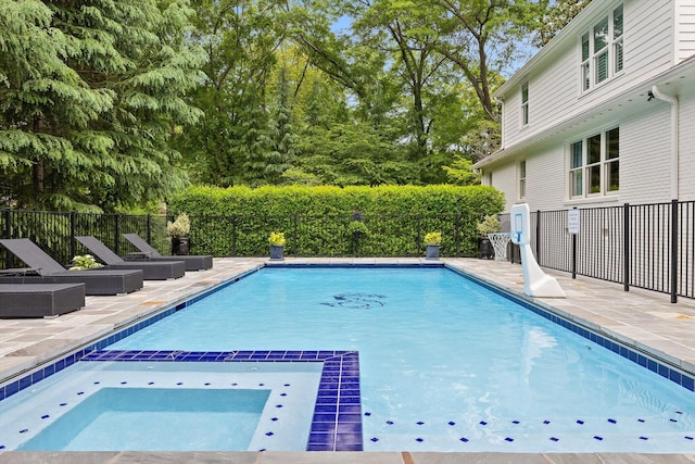 view of swimming pool featuring a pool with connected hot tub, fence, and a patio area