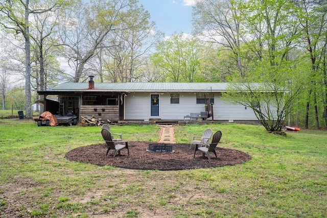 rear view of house with a lawn, a fire pit, and metal roof