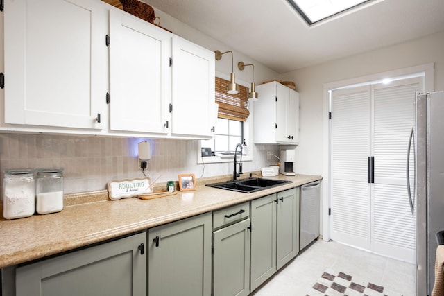 kitchen featuring decorative backsplash, appliances with stainless steel finishes, a sink, light countertops, and white cabinetry
