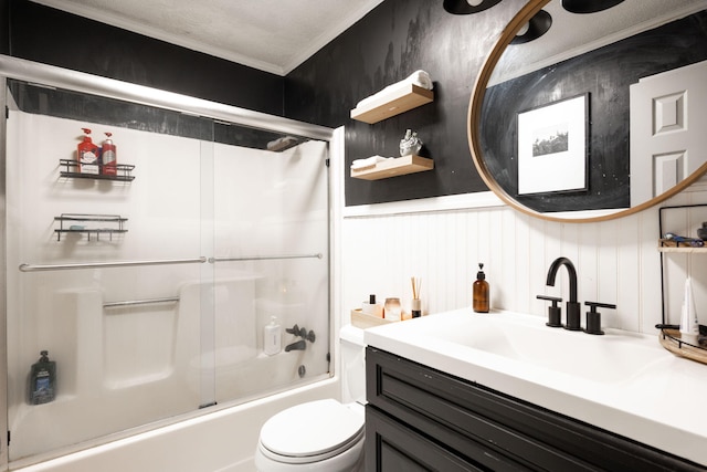 full bath featuring vanity, a wainscoted wall, combined bath / shower with glass door, toilet, and ornamental molding