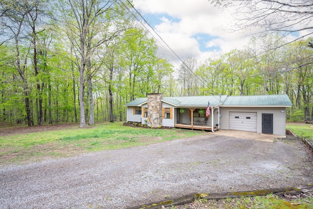 ranch-style home with an attached garage, dirt driveway, a porch, and metal roof