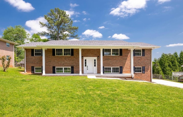 bi-level home featuring brick siding, fence, and a front yard