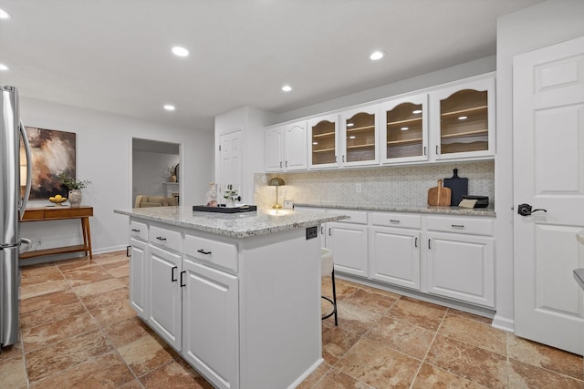 9240 Shay Cv, Ooltewah, TN 37363 - kitchen featuring stone tile floors, a kitchen island, tasteful backsplash, recessed lighting, and white cabinets