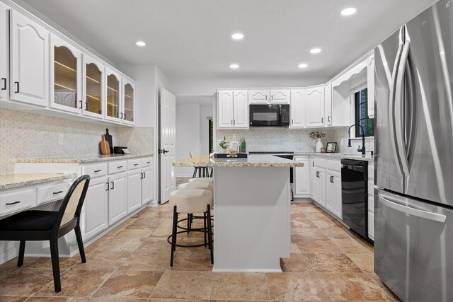 9240 Shay Cv, Ooltewah, TN 37363 - kitchen with black appliances, a sink, glass insert cabinets, a breakfast bar, and tasteful backsplash