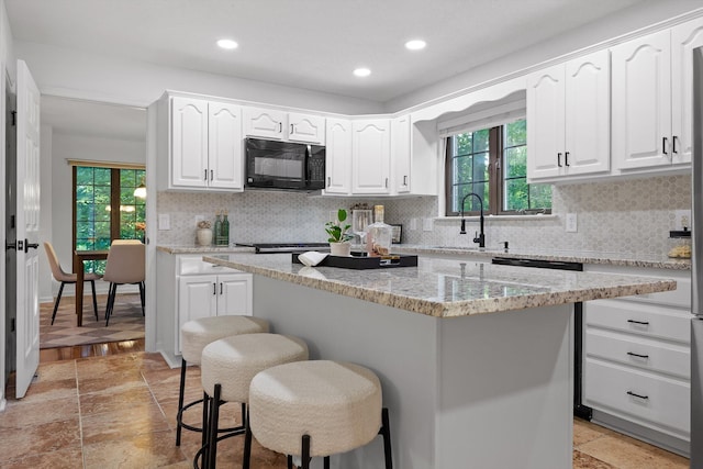 9240 Shay Cv, Ooltewah, TN 37363 - kitchen featuring black microwave, a kitchen breakfast bar, plenty of natural light, white cabinets, and recessed lighting